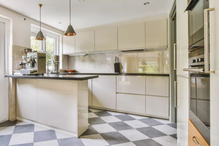 A compact kitchen featuring a checkerboard-patterned tiled floor in a white design