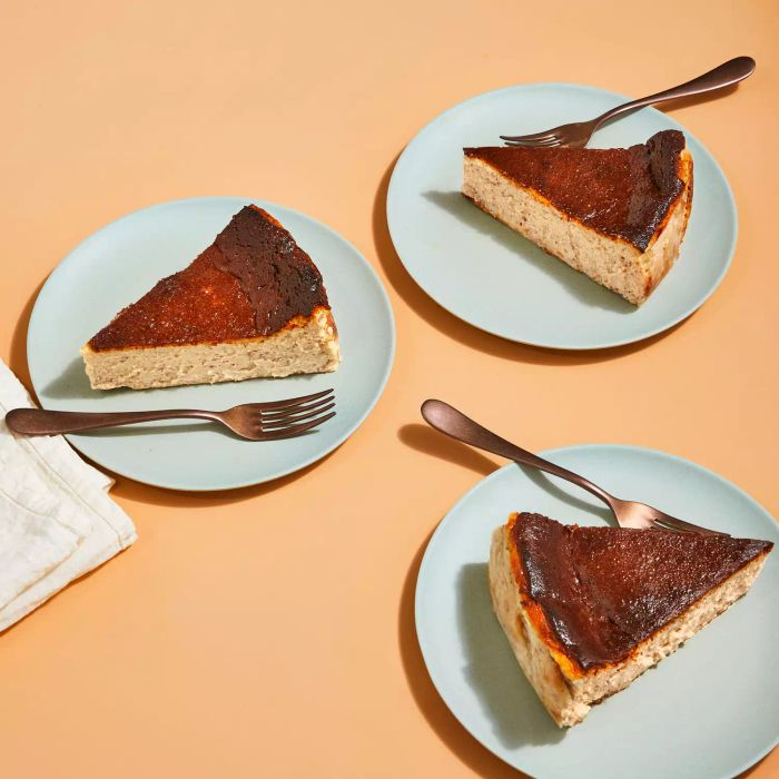 Slices of Orange and Clove Basque Cheesecake elegantly arranged on plates.