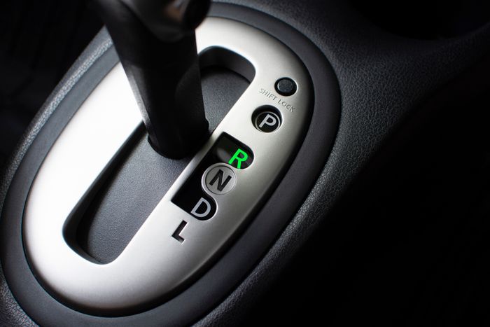A close-up of an automatic car gear shift in park, with indicator lights clearly visible.