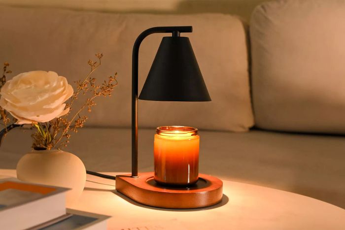 A Sokcvsea Fragrance Candle Warmer Lamp with a glowing amber candle rests on a wooden base