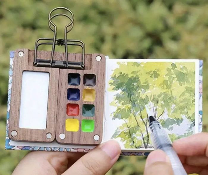 a small watercolor pad paired with a miniature paint set