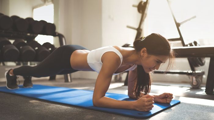 a woman performing a plank exercise solo in a gym