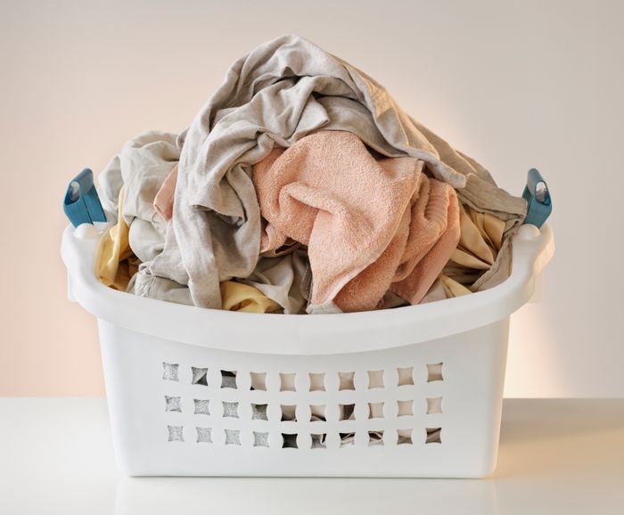 A laundry basket overflowing with a mix of clothes, including a towel.