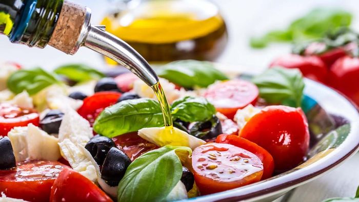 a dish filled with fresh vegetables drizzled with olive oil