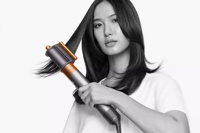 A person is using the Dyson Airwrap Multi-Styler and Dryer Complete Long to create a perfect hairstyle.