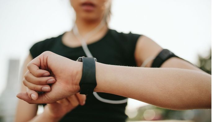 A fitness enthusiast in activewear glancing at her smartwatch