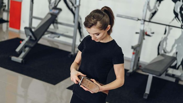 individual securing a weightlifting belt