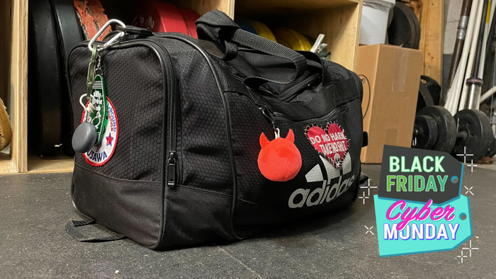 A well-worn (but still looking great) Adidas Defender duffel bag adorned with patches and keychains.