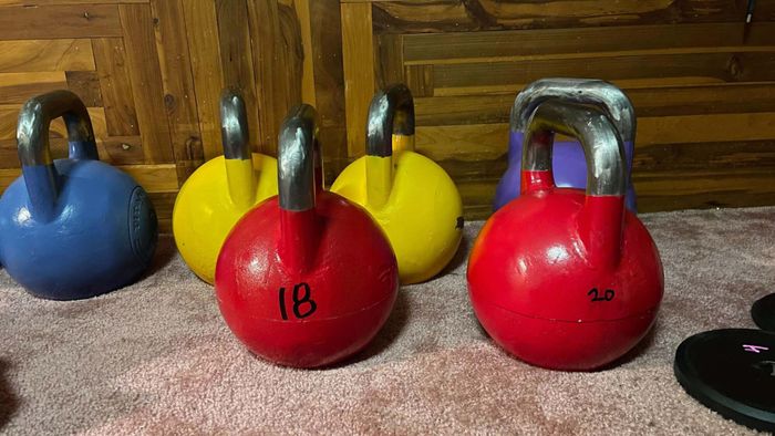 Two red adjustable kettlebells, one marked 18 and the other 20.