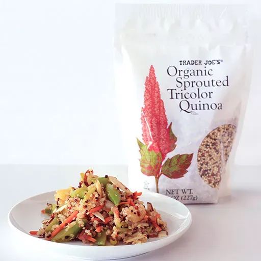 Package of Organic Sprouted Tricolored Quinoa next to a plate of cooked quinoa served with stir-fry vegetables