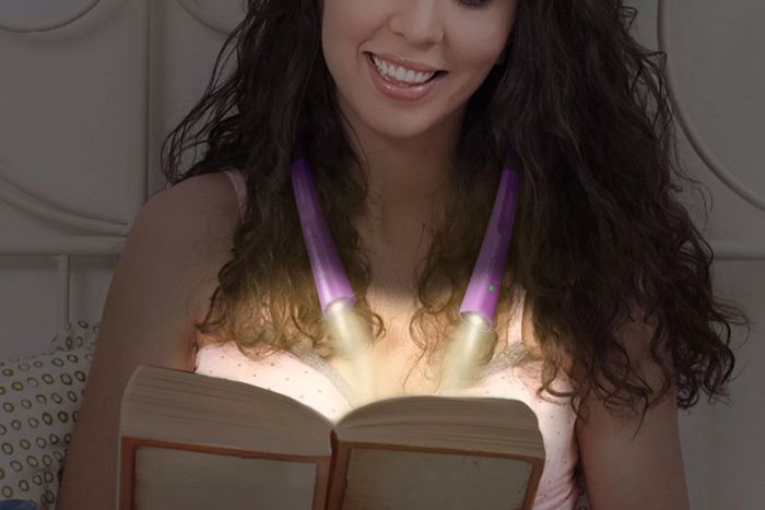A person reading a book while wearing the Glocusent Upgraded LED Neck Reading Light