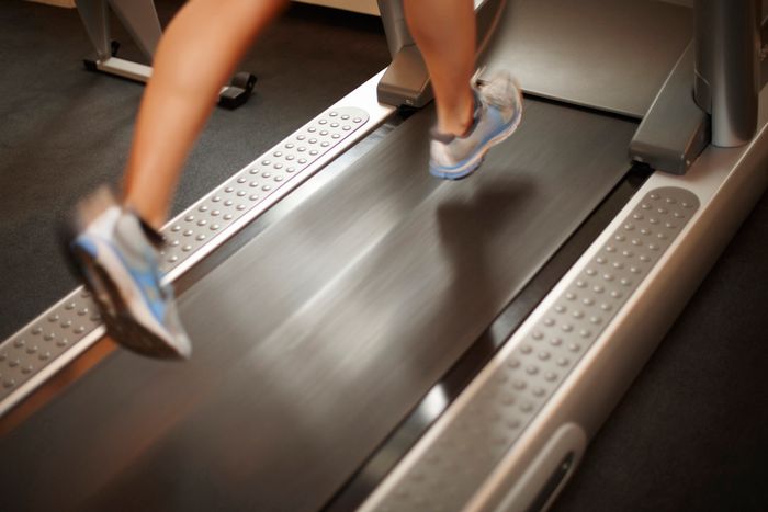 Person running on a treadmill, focused on their lower legs and feet in athletic shoes