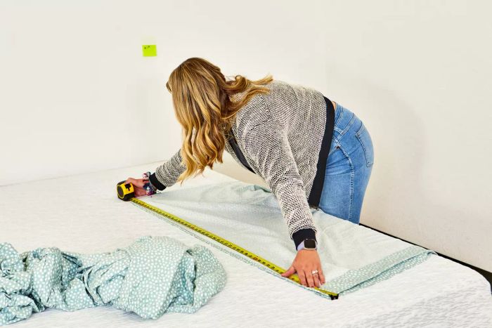 A person measuring the True North by Sleep Philosophy Flannel Sheet Set with a tape measure