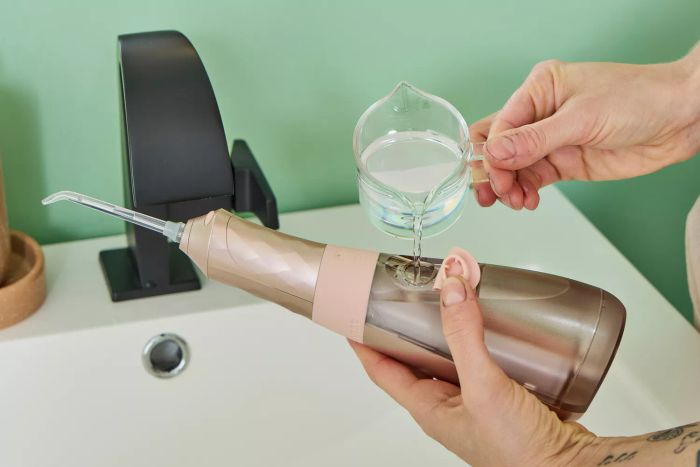 A person filling the water tank of the Burst Water Flosser