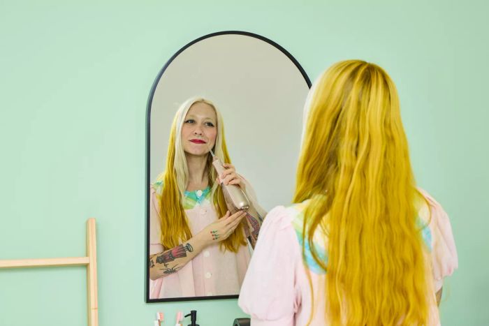 A user operating the Burst Water Flosser while checking their reflection in a mirror