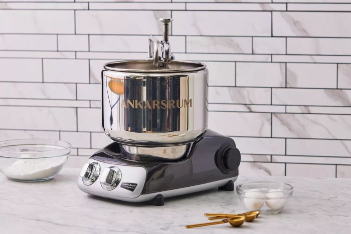 Ankarsrum Original Kitchen Machine placed on a marble countertop beside a dish containing eggs and flour
