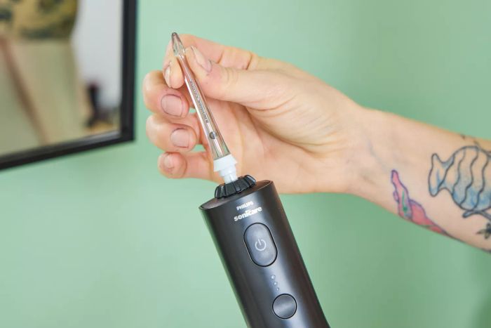 A hand gripping the upper section of the Philips Sonicare Cordless Power Flosser 3000