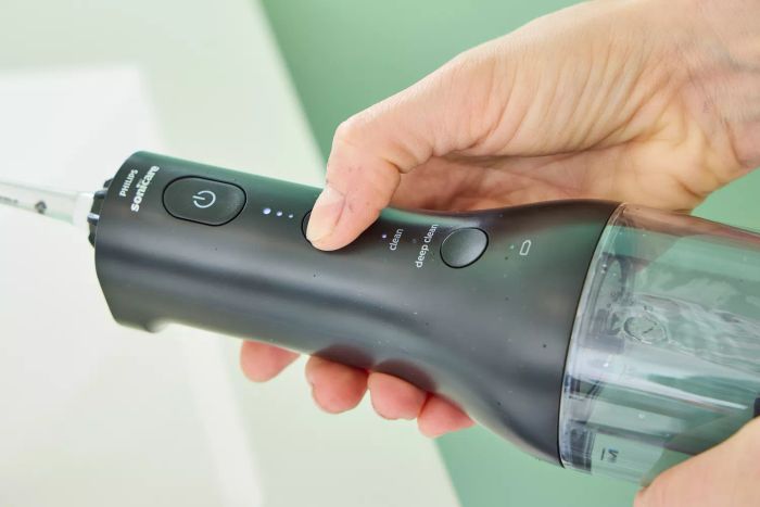 A detailed shot of a hand adjusting a button on the Philips Sonicare Cordless Power Flosser 3000