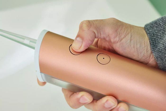 A hand gripping the Quip Rechargeable Cordless Water Flosser