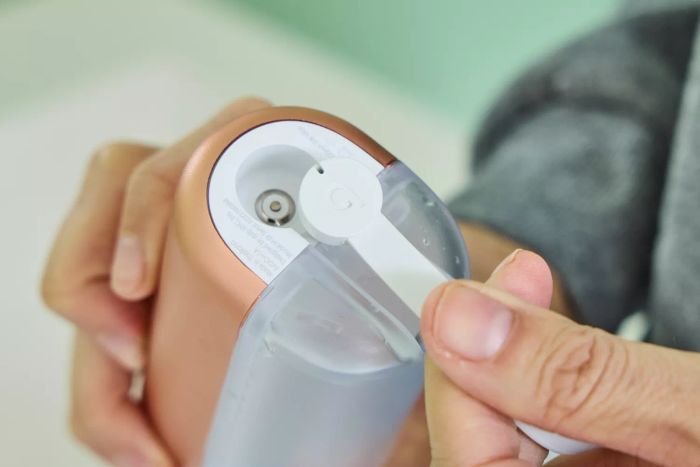 A hand detaching the cord from the Quip Rechargeable Cordless Water Flosser
