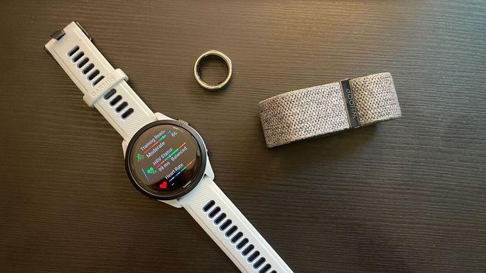 Garmin Forerunner 265, Oura ring, and Whoop band placed together on a desk
