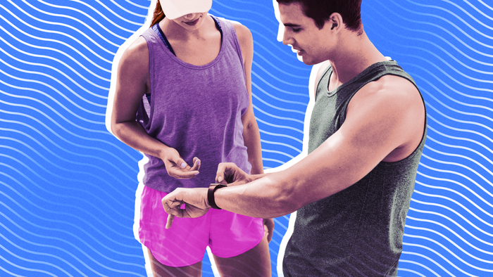 A man and woman dressed in running attire, engaged in conversation while examining the man's fitness tracker