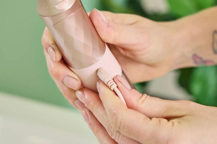A hand holding the cord of the Burst Water Flosser