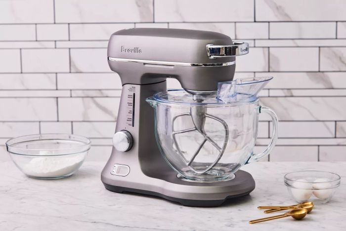 Breville Bakery Chef Stand Mixer on display on a kitchen counter with mixing bowls and measuring spoons.