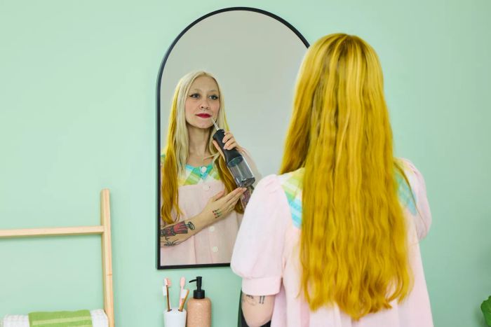 A user operating the Philips Sonicare Cordless Power Flosser 3000 while checking their reflection in a mirror