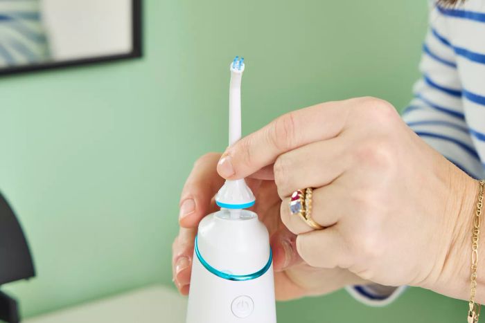A detailed view of hands swapping the nozzle on the Zima Dental Hydropod Smart Water Flosser
