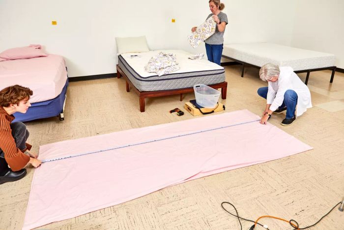 Two individuals measuring a sheet from the Lands’ End Comfy Super Soft Cotton Flannel Sheet Set