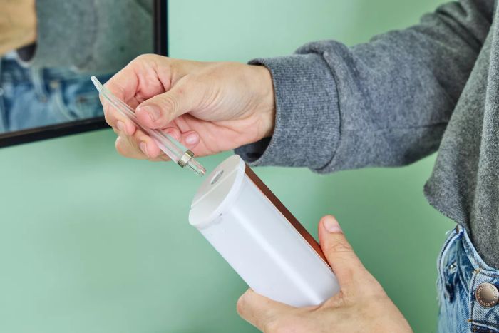 A hand holding a nozzle for the Quip Rechargeable Cordless Water Flosser