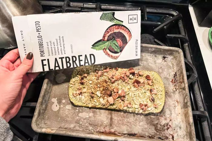 A person holding the cooking instructions for a Daily Harvest Meal Kit flatbread