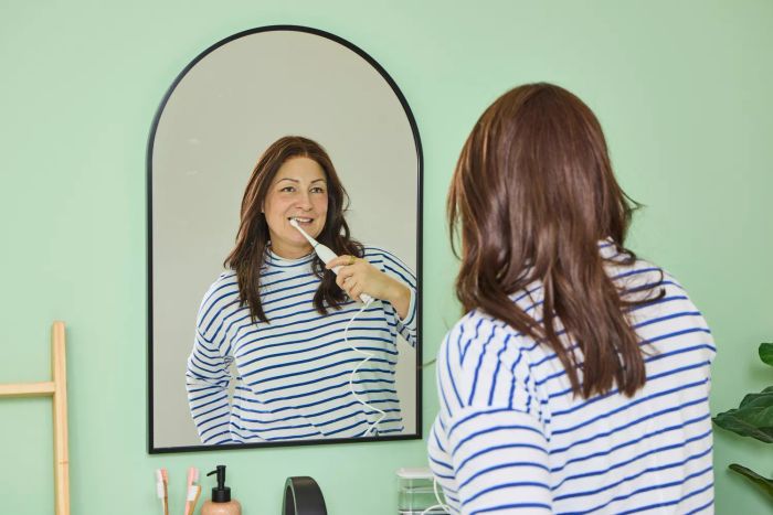 A user brushing their teeth using the Waterpik Sonic-Fusion 2.0 Professional while looking into a mirror