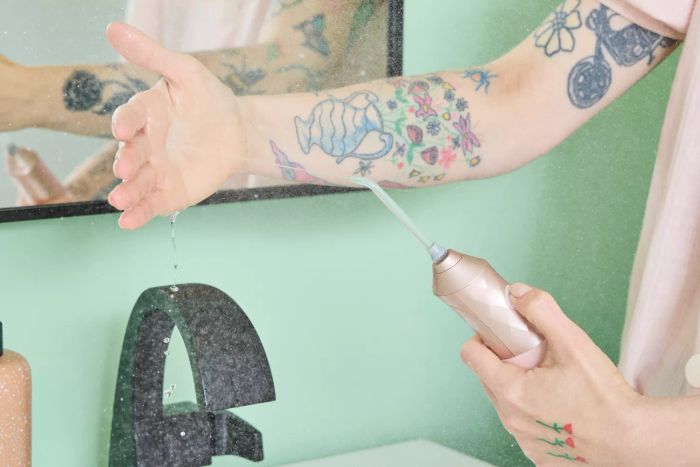 A user testing the Burst Water Flosser by spraying water into their hand