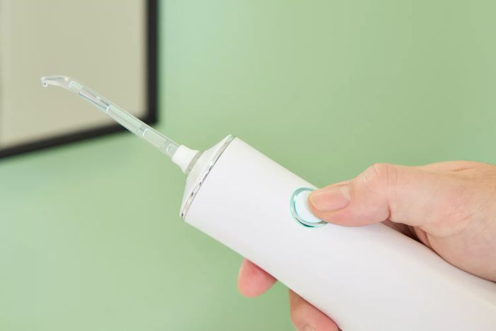 A hand adjusting a button on the BOKA Power Flosser