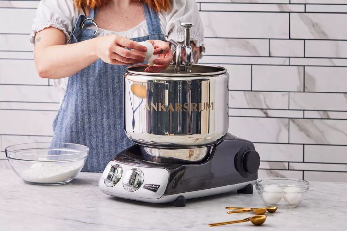 A person cracking an egg into the Ankarsrum Original Kitchen Machine