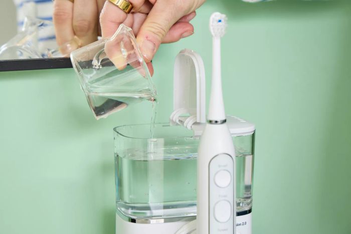 A user filling the water tank of the Waterpik Sonic-Fusion 2.0 Professional