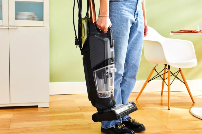 A hand holding the Bissell CrossWave HydroSteam Plus Multi-Surface Wet Dry Vac above a wooden floor.