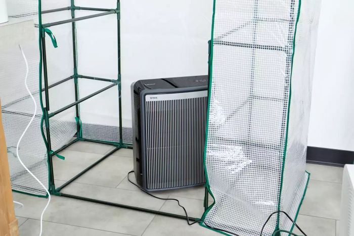 The Winix 9800 4-Stage True HEPA Air Purifier with WiFi & PlasmaWave Technology showcased on a tiled floor inside a plastic enclosure