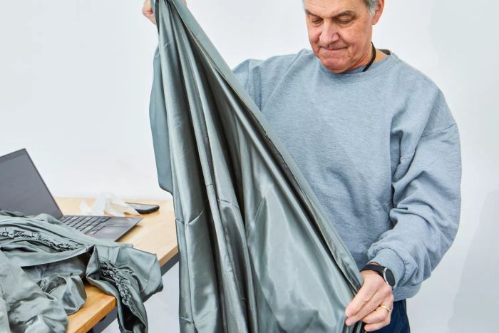 A person holding Lanest Housing Silk Satin Sheets near a table with a laptop