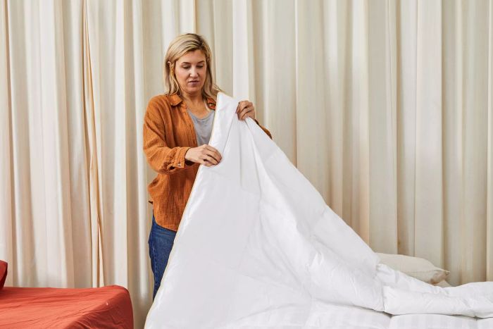 A person holding one edge of the Alwyn Home All Season Down Comforter.