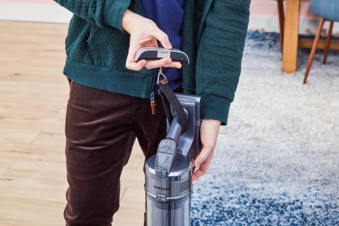A person measuring the weight of the Samsung Jet 90 Vacuum