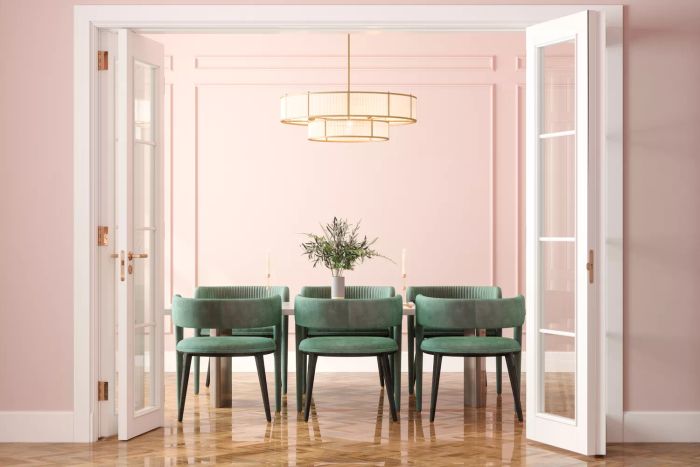 Dining Room Entrance Featuring a Dining Table, Green Velvet Chairs, and a Pink Wall as a Backdrop