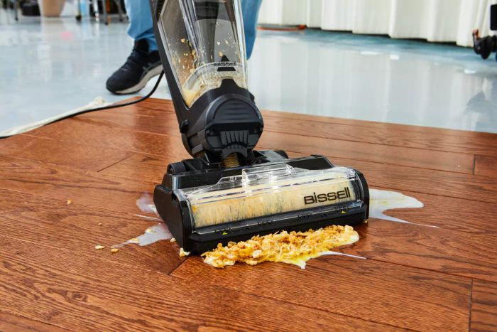 The Bissell CrossWave HydroSteam Plus in action, cleaning up spilled cereal and milk on a wooden floor.