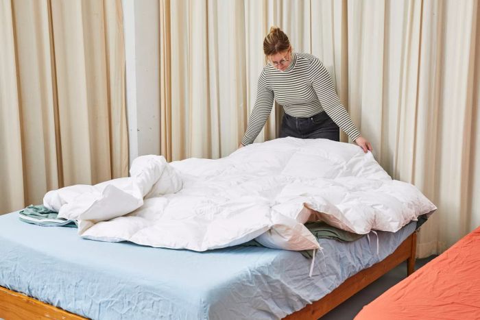 A person adjusting sections of the Casaluna Premium Down Comforter on the bed.