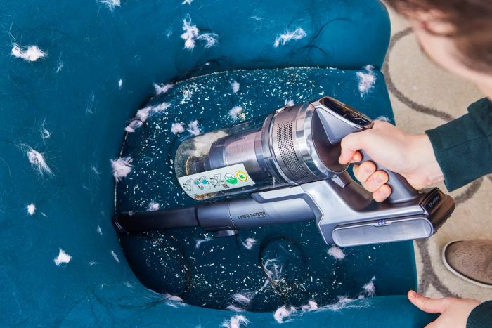 A person using the Samsung Jet 90 Vacuum to clean a chair