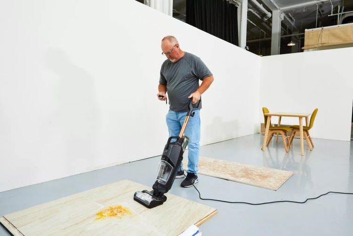 A person using the Bissell CrossWave HydroSteam Plus to clean wet food spills from a wooden floor.