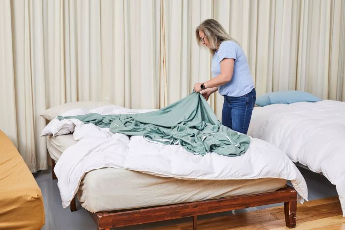 A person arranging a bed using the Egyptian Bedding Luxurious Queen Size Goose Down Feather Comforter