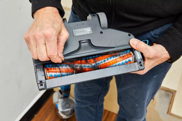 A close-up of hands removing tangled hair from the brush roll of the BLACK+DECKER Powerseries Extreme Cordless Stick Vacuum Cleaner